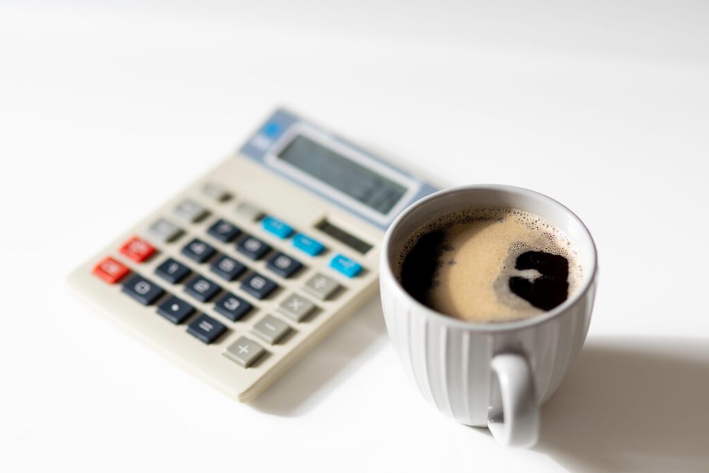 calculator next to a cup of black coffee