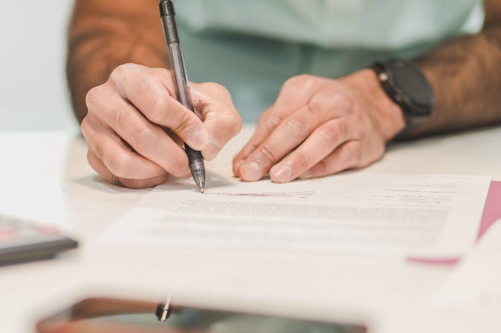 man writing an exit strategy with pen and paper